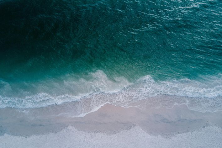 Stunning aerial shot of turquoise ocean waves washing onto a pristine sandy beach, perfect for backgrounds.